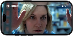 Un iPhone 18 Pro en orientation paysage, affichant un gros plan d’une femme qui regarde par une fenêtre. Titre de la série : Pluribus.