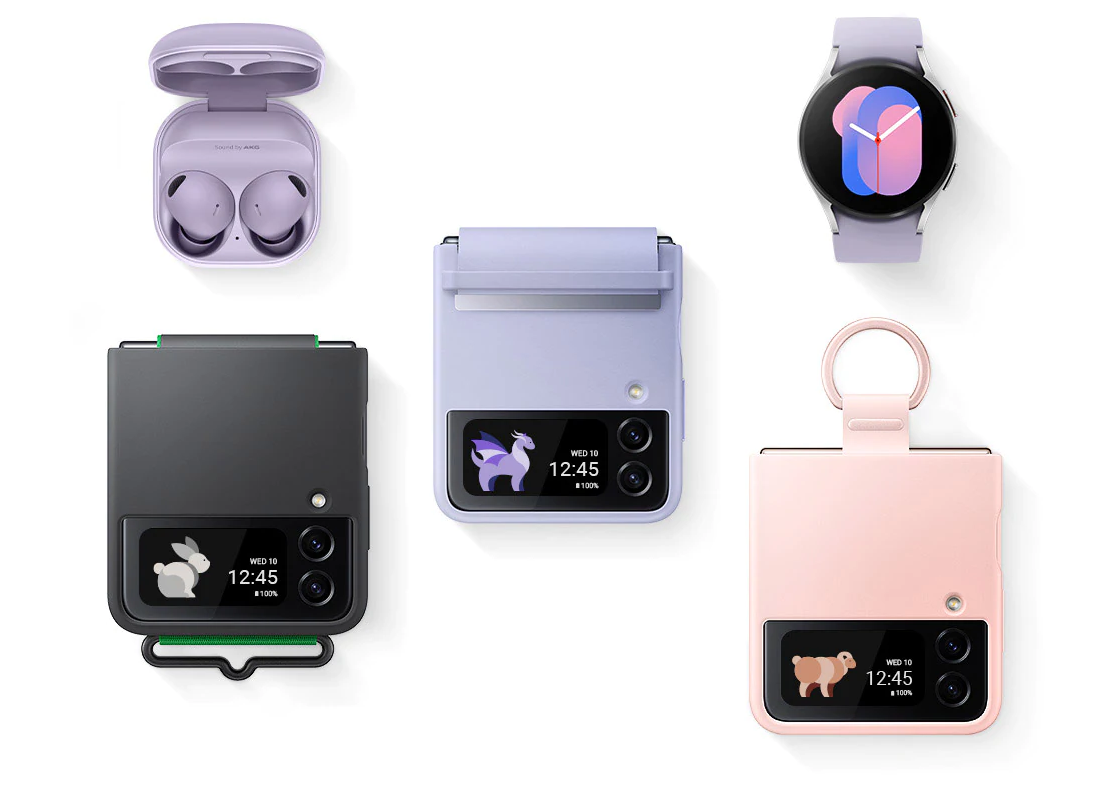 An overhead angle of
	Galaxy Buds2 Pro with the cradle open and the earbuds in place. Three Galaxy Z Flip4 devices are folded, Cover Screen
	facing upwards. Each has a different phone case installed: a Black Silicone Cover with Strap, a Serene Purple Flap
	Leather Cover, and a Pink Silicone Cover with Ring. A Galaxy Watch5 with a graphic watch face.