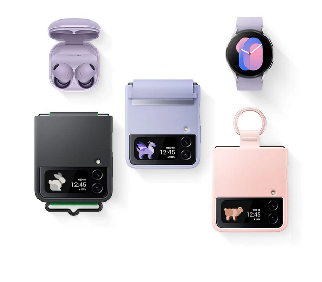 An overhead angle of
	Galaxy Buds2 Pro with the cradle open and the earbuds in place. Three Galaxy Z Flip4 devices are folded, Cover Screen
	facing upwards. Each has a different phone case installed: a Black Silicone Cover with Strap, a Serene Purple Flap
	Leather Cover, and a Pink Silicone Cover with Ring. A Galaxy Watch5 with a graphic watch face.