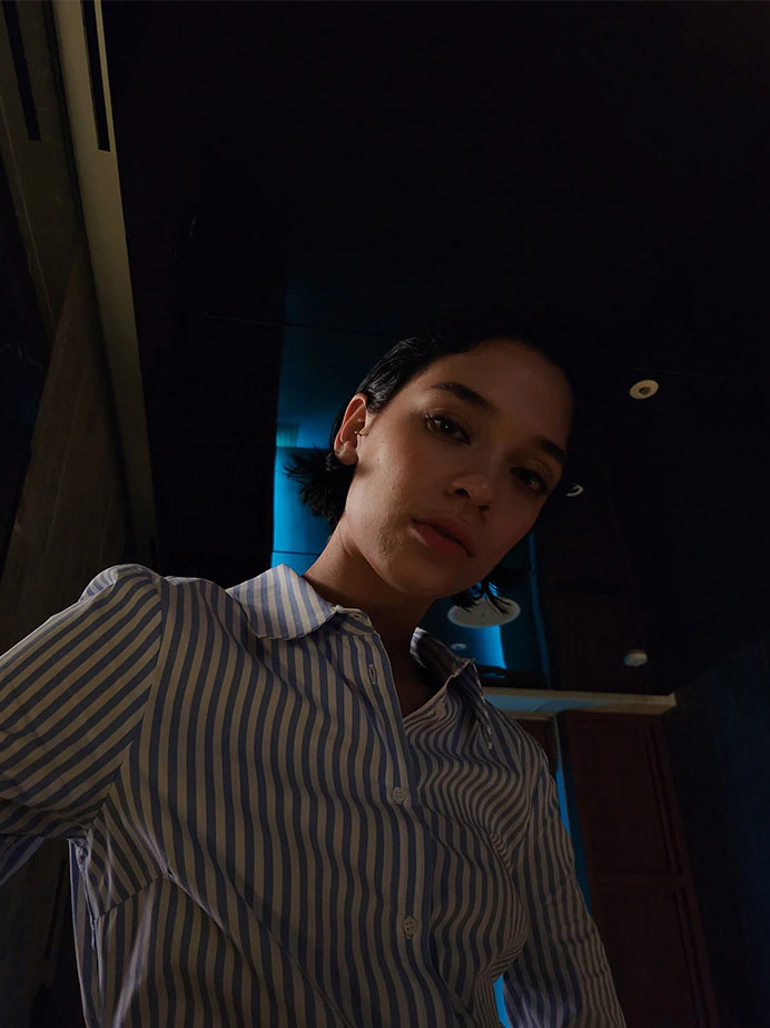 A woman takes a selfie
						in a dark setting. The colours are bright and her features are clear thanks to Nightography.