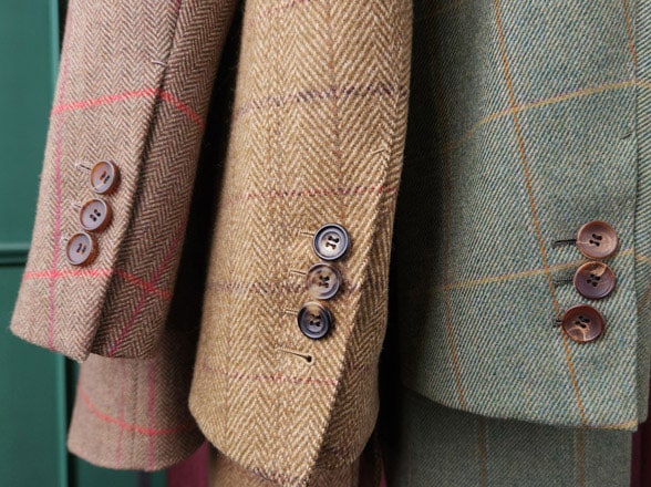 Three jackets
				in different colours with windowpane check patterns hang next to each other. The high resolution of the photo allows
				the texture of the fabric to be seen clearly.