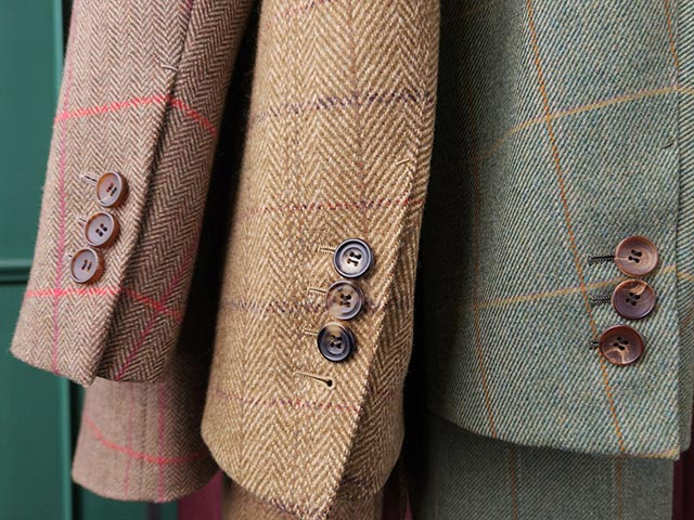Three jackets
				in
				different colours with windowpane check patterns hang next to each other. The high resolution of the photo allows
				the texture of the fabric to be seen clearly.