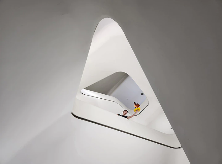 A view looking
				up a circular staircase of a large, modern building. Many floors up, a man is seen leaning over the handrails.
				Another man is seen with his arm extended over the railing, catching a yellow hat that seems to have fallen from
				above. Next is a close up of the man at the top of the staircase. With 30 X Space Zoom, the photo captures his
				shocked expression in reaction to dropping his hat.