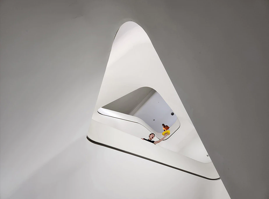 A view looking up
				a circular staircase of a large, modern building. Many floors up, a man is seen leaning over the handrails. Another
				man is seen with his arm extended over the railing, catching a yellow hat that seems to have fallen from above. Next
				is a close up of the man at the top of the staircase. With 30 X Space Zoom, the photo captures his shocked
				expression in reaction to dropping his hat.
