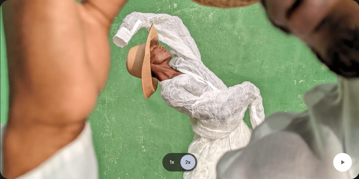 A person tips their hat in the foreground while another person dances in the background. The camera zooms in
					on the person dancing in the background