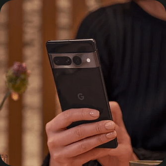 A hand holds a Pixel 7 Pro with notifications for an Uber arriving and a text message