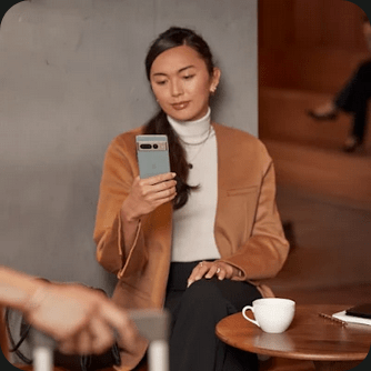 A person drinking coffee looks at their Pixel 7 Pro