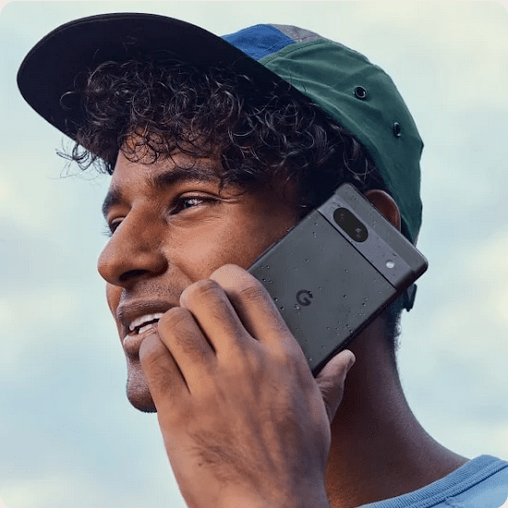 A person outside smiling and having a conversation on a Pixel 7a in the color Charcoal.