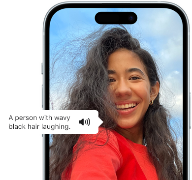 Un iPhone 15 affichant la fonctionnalité VoiceOver en train de lire les renseignements d’une image : Une personne avec les cheveux noirs ondulés en train de rire.